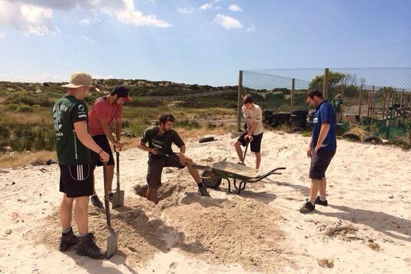 A group of Projects Abroad volunteers dig sand for building a new community center in Cape Town, South Africa.