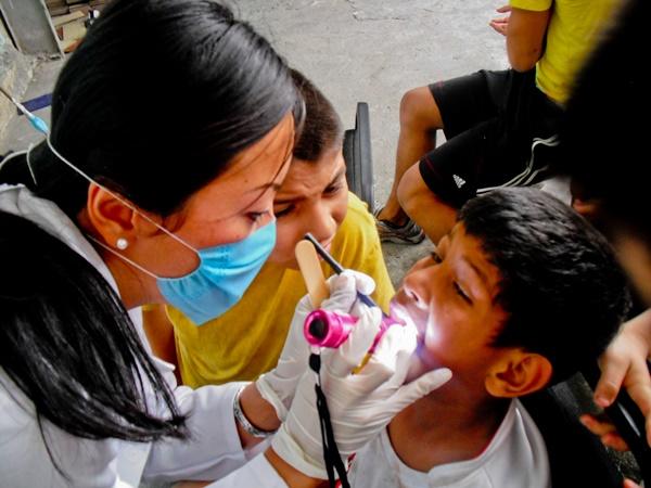 Volunteer on a Dentistry Project Working with a Child A Projects Abroad volunteer conducts a dental checkup for a child at a medical outreach in Guadalajara, Mexico.