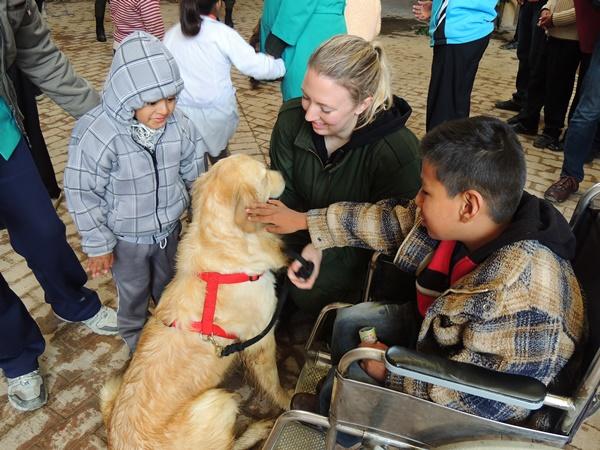 A female volunteer helps disabled children interact with a trained therapy dog on the Canine Therapy Project in Bolivia Bolivian children pet a therapy dog under the supervision of a Canine Therapy volunteer