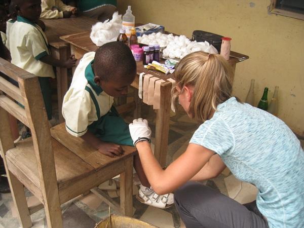 Intern on a Public Health Project Puts a Bandage on a Child in Ghana Public Health Intern dressing a child's wound in a village in Ghana