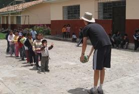 Care A 19+ Care & Community volunteer in Peru plays a ball game with young children.
