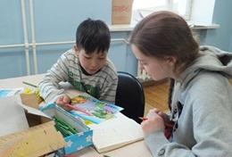 Mongolia A High School Special Care & Community volunteer assists a young child with an activity in Mongolia.