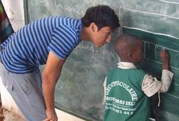 Senegal In Senegal, a Care & Community High School Special student volunteer helps a boy as he writes on the blackboard.