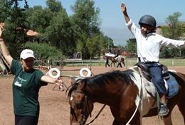 Care An Equine Therapy & Community student volunteer on the High School Special helps a young boy gain confidence on a horse.