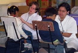 Medicine & Healthcare High School Special Medicine volunteers in Bolivia check young children's heartbeats.