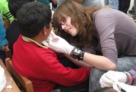 Peru A volunteer on the Medicine High School Special in Peru checks a boy's wound.