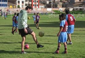 Sports Volunteer Coaching Soccer with Projects Abroad Volunteer on the Sports project coaches young boy in soccer overseas
