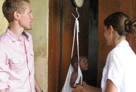 Medicine & Healthcare Intern on the Ghana Medical Internship help during a medical outreach by weighing a baby.