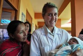 Peru A Midwifery volunteer in Peru holds a baby as a staff member looks on.