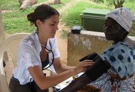 Medicine & Healthcare In Ghana, a nursing intern takes an older woman's pressure reading.