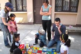 Care Professional social workers explain a game to children in Bolivia.