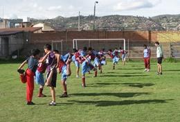 Teaching A professional PE teacher volunteering in Peru leads children through soccer drills during class.